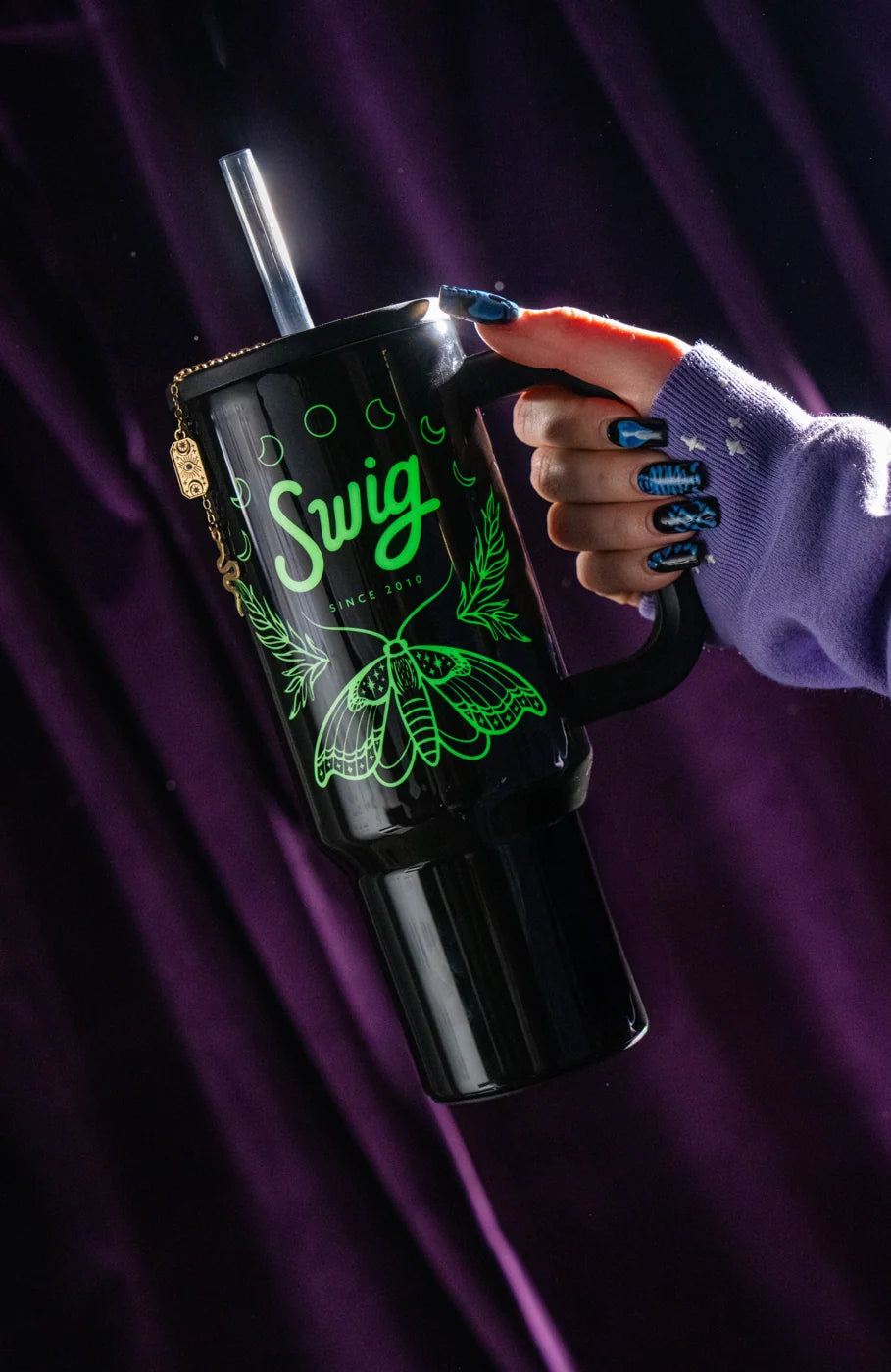After dark: the Witching Hour Tumbler's moth and moon artwork glow green against purple curtains.