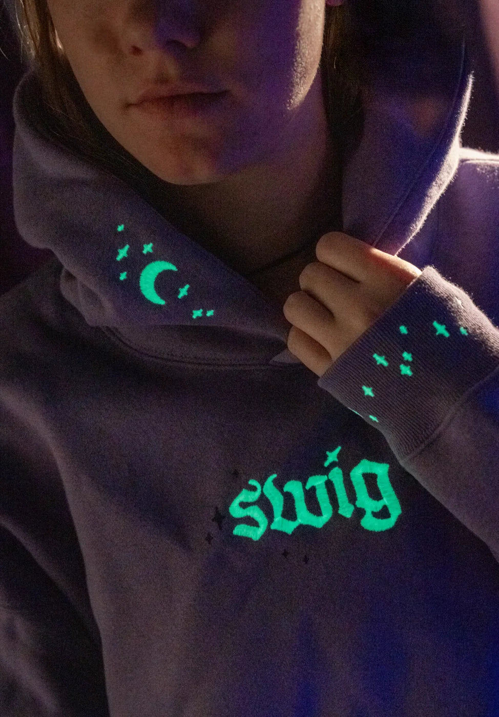 After dark: the hood, cuff, and chest artwork glow green on the purple hoodie.